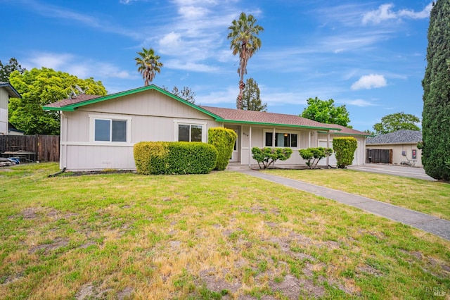 ranch-style home featuring concrete driveway, fence, a front lawn, and a garage