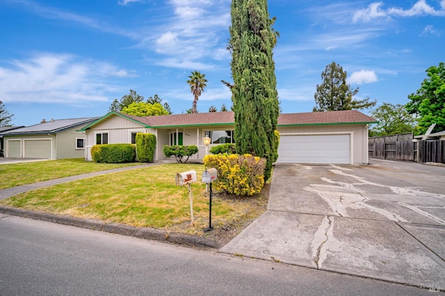ranch-style house featuring fence, an attached garage, driveway, and a front yard
