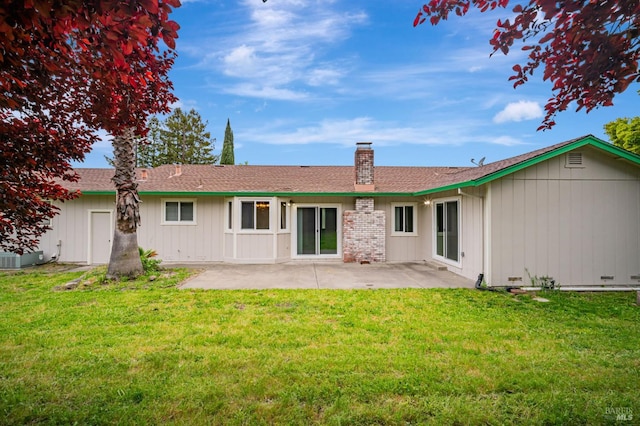 rear view of house featuring a chimney, a yard, and a patio area