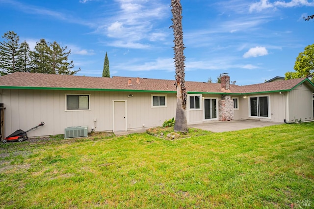rear view of property featuring a lawn, a patio, central AC, and a chimney