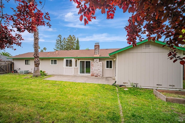 back of property with a yard, fence, a chimney, and a patio area