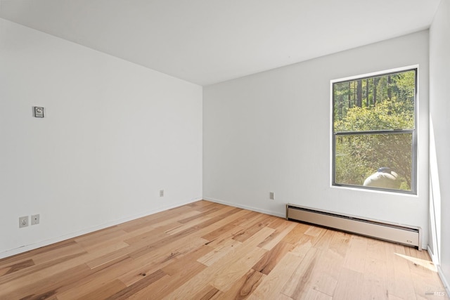 empty room featuring light wood finished floors, baseboards, and a baseboard radiator