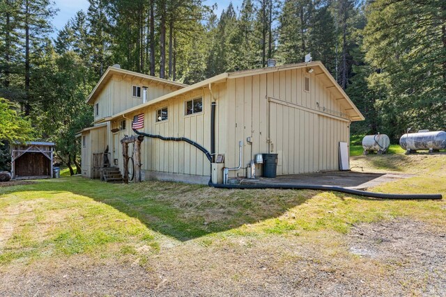 view of side of home featuring board and batten siding, a lawn, aphalt driveway, and a garage