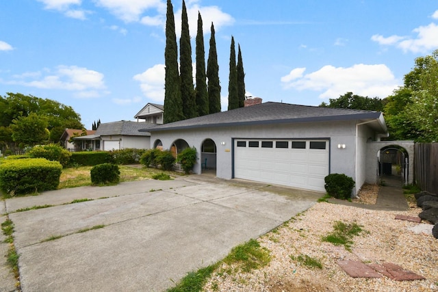 view of front of home with an attached garage, a chimney, stucco siding, and driveway