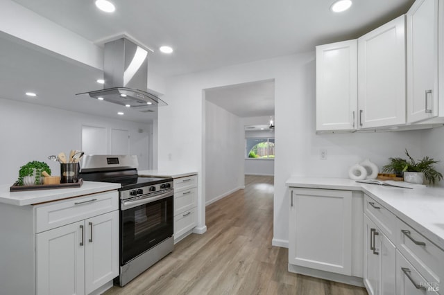 kitchen featuring island range hood, stainless steel range with electric cooktop, white cabinets, and light countertops