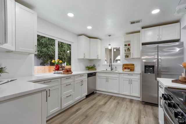 kitchen with a sink, light wood-type flooring, stainless steel appliances, white cabinets, and visible vents