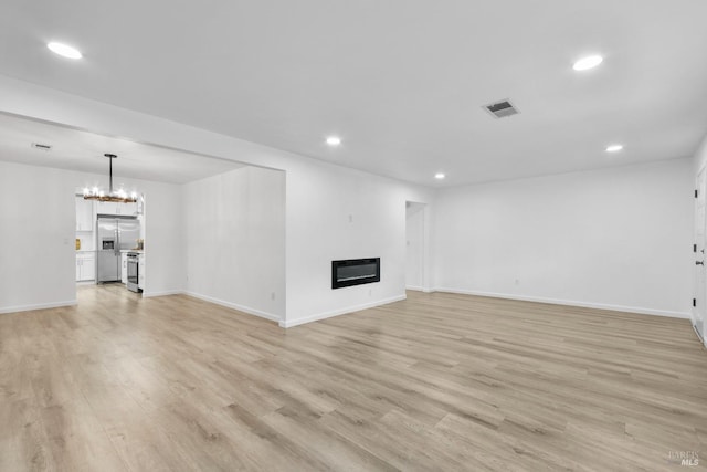 unfurnished living room featuring recessed lighting, a glass covered fireplace, light wood-type flooring, and visible vents
