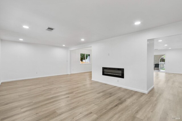 unfurnished living room with recessed lighting, visible vents, a wealth of natural light, and heating unit