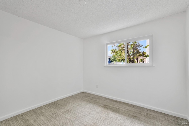 carpeted spare room featuring baseboards and a textured ceiling