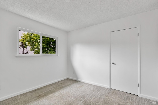carpeted empty room with baseboards and a textured ceiling