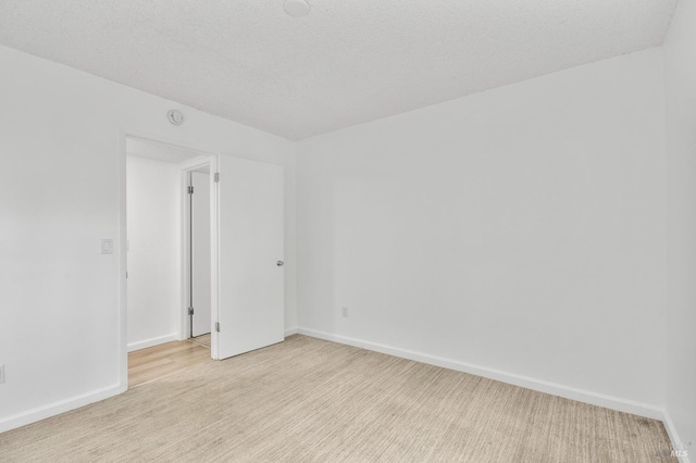 spare room with baseboards and light colored carpet