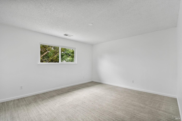 carpeted spare room with baseboards, a textured ceiling, and visible vents