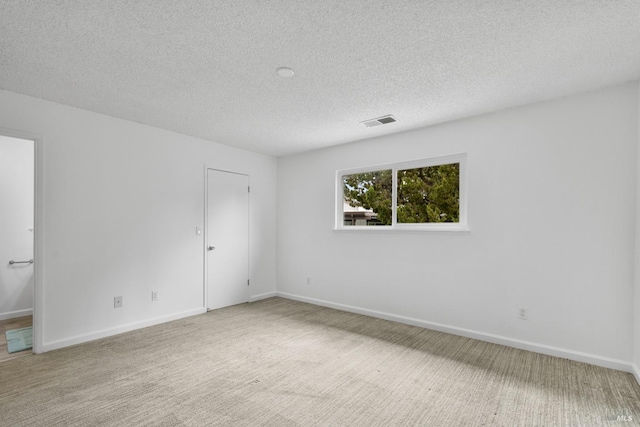 spare room with a textured ceiling, carpet floors, visible vents, and baseboards