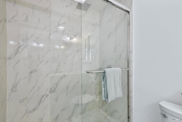 bathroom featuring toilet and a marble finish shower