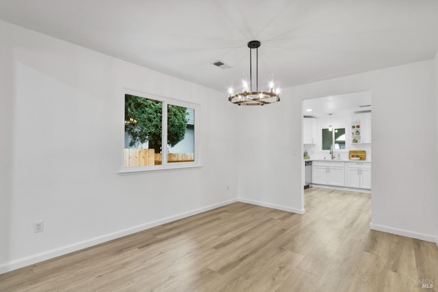 unfurnished dining area with a sink, light wood-style floors, baseboards, a notable chandelier, and visible vents