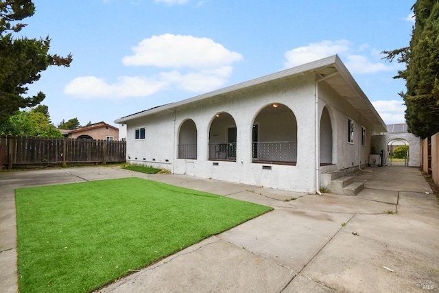 rear view of house with a yard, stucco siding, and fence