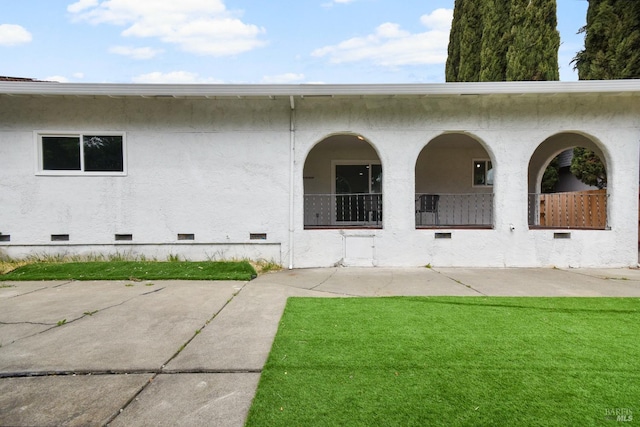 exterior space featuring a yard, crawl space, and stucco siding