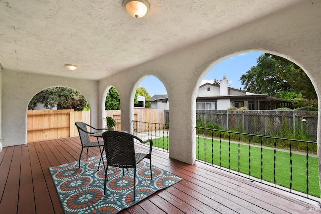 wooden terrace featuring a lawn and fence