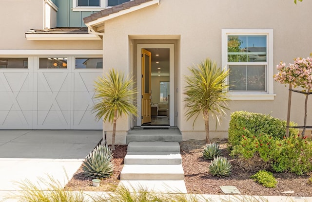view of exterior entry featuring a tile roof, concrete driveway, and stucco siding
