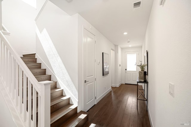 corridor featuring dark wood finished floors, baseboards, visible vents, recessed lighting, and stairway