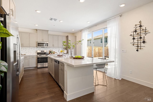 kitchen with a sink, dark wood-style flooring, tasteful backsplash, visible vents, and appliances with stainless steel finishes