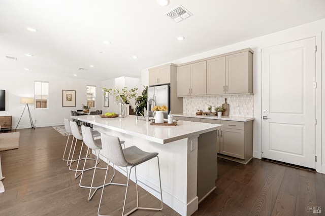 kitchen featuring dark wood-style flooring, visible vents, backsplash, gray cabinetry, and stainless steel refrigerator with ice dispenser