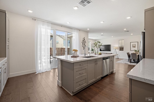 kitchen featuring a sink, a center island with sink, appliances with stainless steel finishes, gray cabinetry, and visible vents