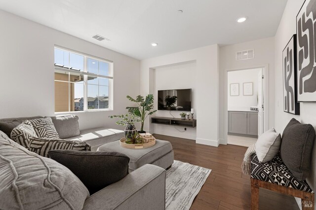 living area with wood finished floors, visible vents, and recessed lighting