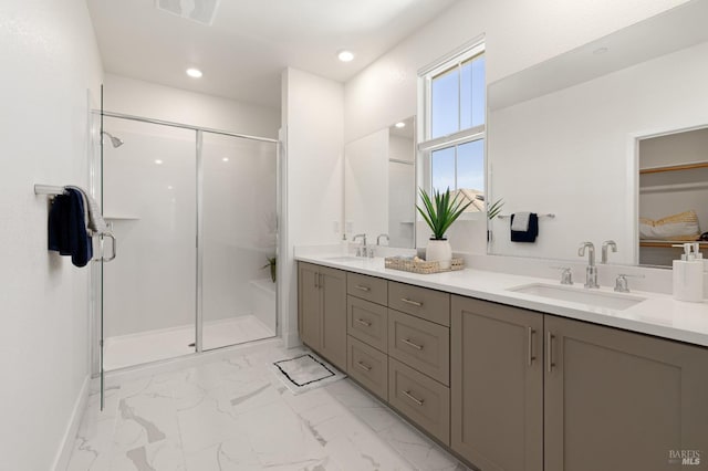 bathroom featuring marble finish floor, a sink, a shower stall, and double vanity