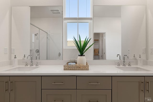 bathroom with double vanity, visible vents, a stall shower, and a sink