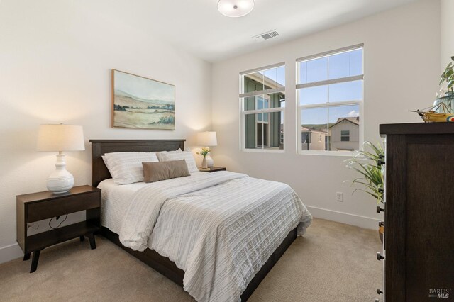 bedroom with baseboards, visible vents, and light colored carpet