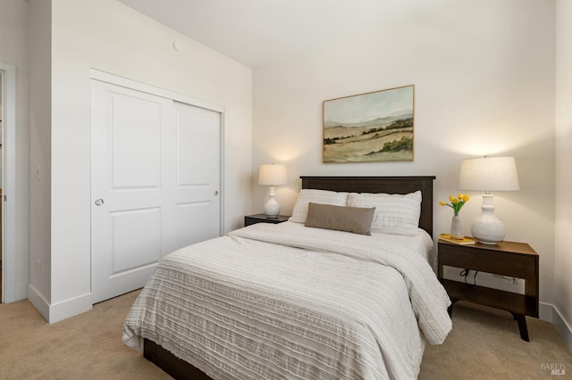 bedroom featuring light carpet, baseboards, and a closet