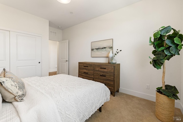 bedroom with a closet, baseboards, visible vents, and light colored carpet