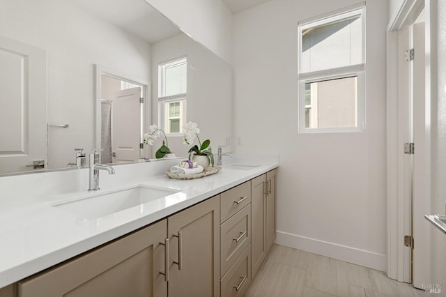 full bath featuring baseboards, a sink, and double vanity