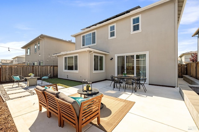 back of property with an outdoor living space with a fire pit, a fenced backyard, a patio area, outdoor dining area, and stucco siding