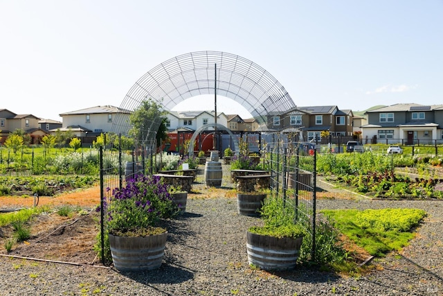 view of property's community with fence, a vegetable garden, and a residential view