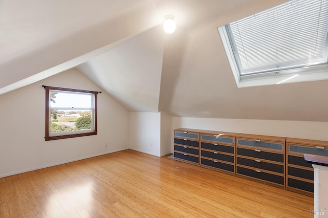 bonus room featuring lofted ceiling with skylight, wood finished floors, and baseboards