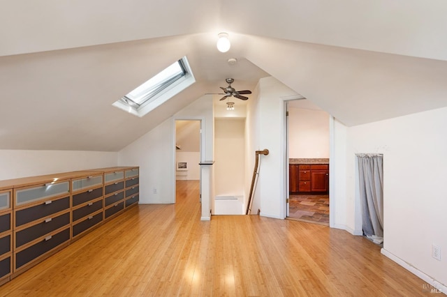 bonus room with vaulted ceiling with skylight, light wood finished floors, and a ceiling fan