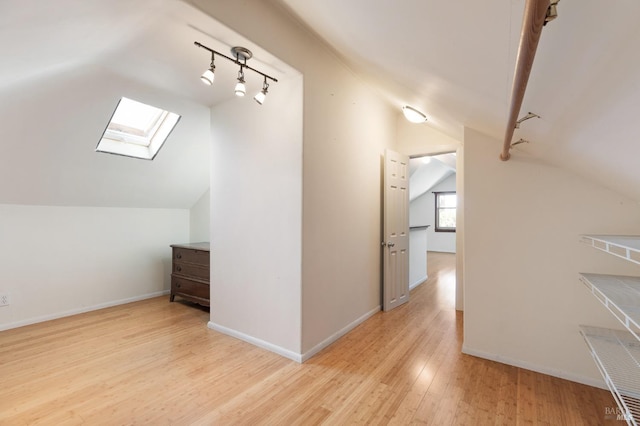 bonus room featuring baseboards, wood finished floors, and vaulted ceiling with skylight