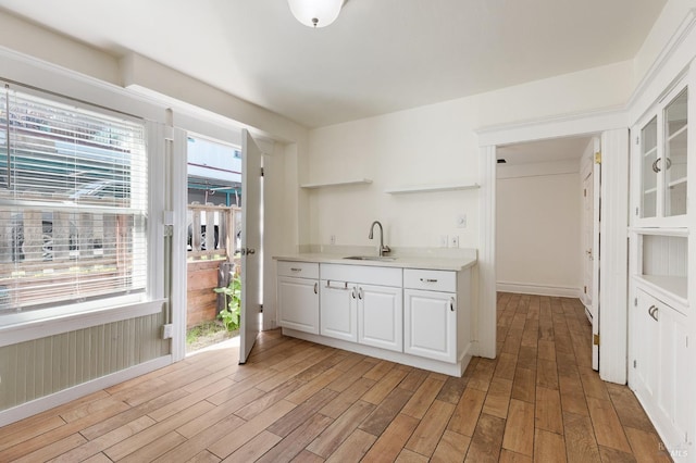 kitchen with light wood-style floors, open shelves, a sink, and light countertops