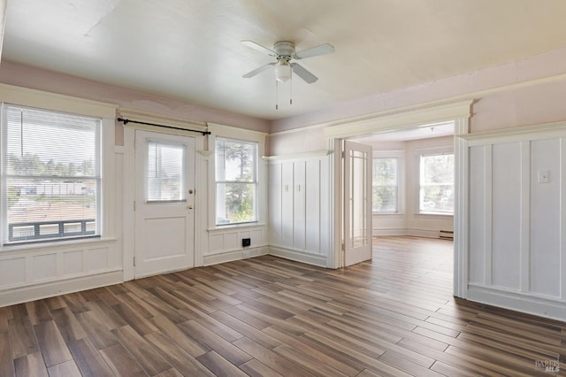 foyer featuring wood finished floors, a decorative wall, and a ceiling fan