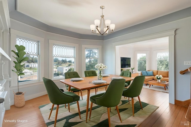 dining space with light wood-style flooring, baseboards, and a notable chandelier
