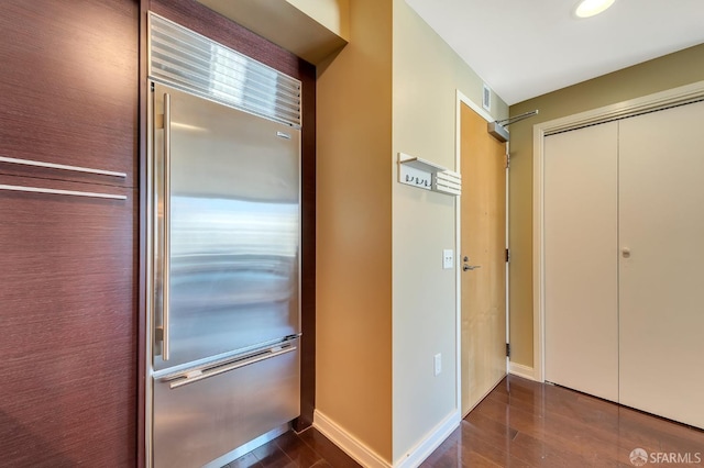 corridor featuring dark wood-type flooring and baseboards