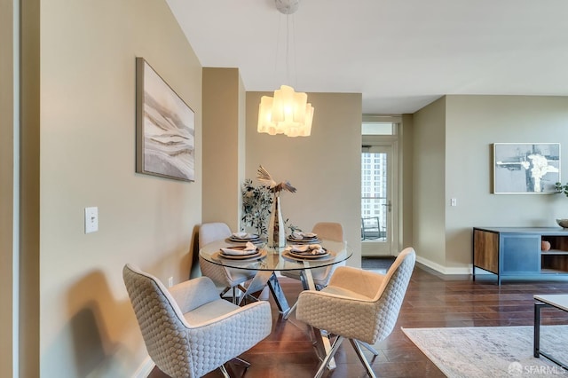 dining space with a chandelier, dark wood-style floors, and baseboards