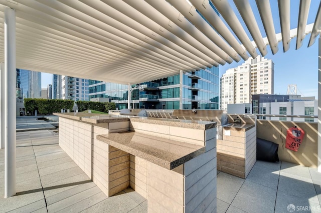 view of patio with a city view, an outdoor kitchen, and exterior bar