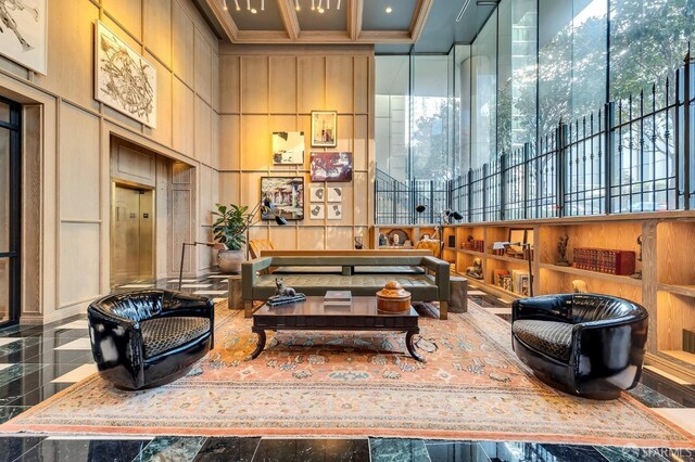 community lobby featuring a high ceiling, a decorative wall, coffered ceiling, crown molding, and beamed ceiling
