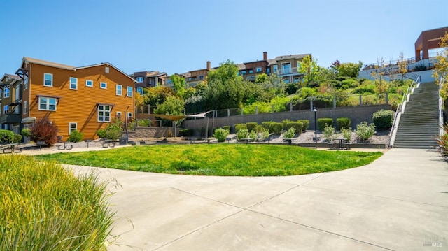 surrounding community featuring fence, a yard, stairs, and a residential view