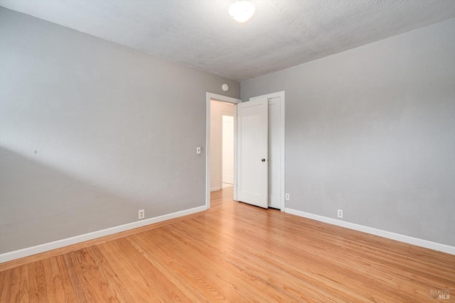 spare room with baseboards and light wood finished floors