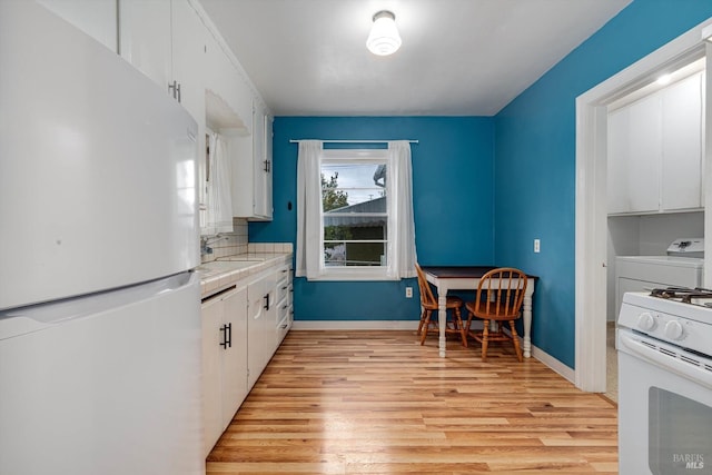 kitchen with light wood finished floors, tile countertops, white cabinetry, and white appliances