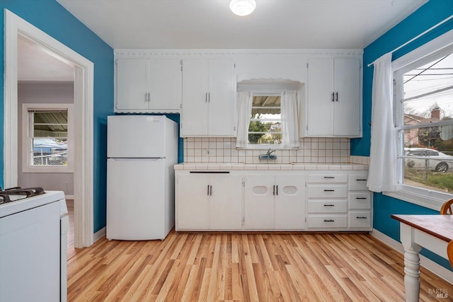 kitchen with tile counters, light wood-style floors, white cabinetry, and white appliances